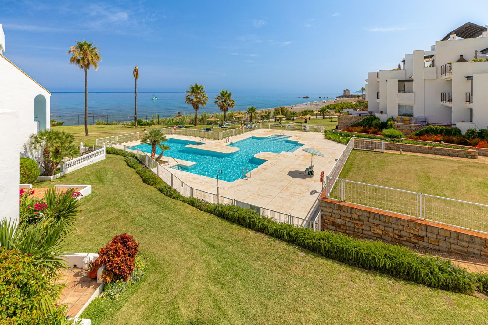 Gemeinschaftspool und Gärten der Wohnanlage Casares Costa, dahinter das Mittelmeer